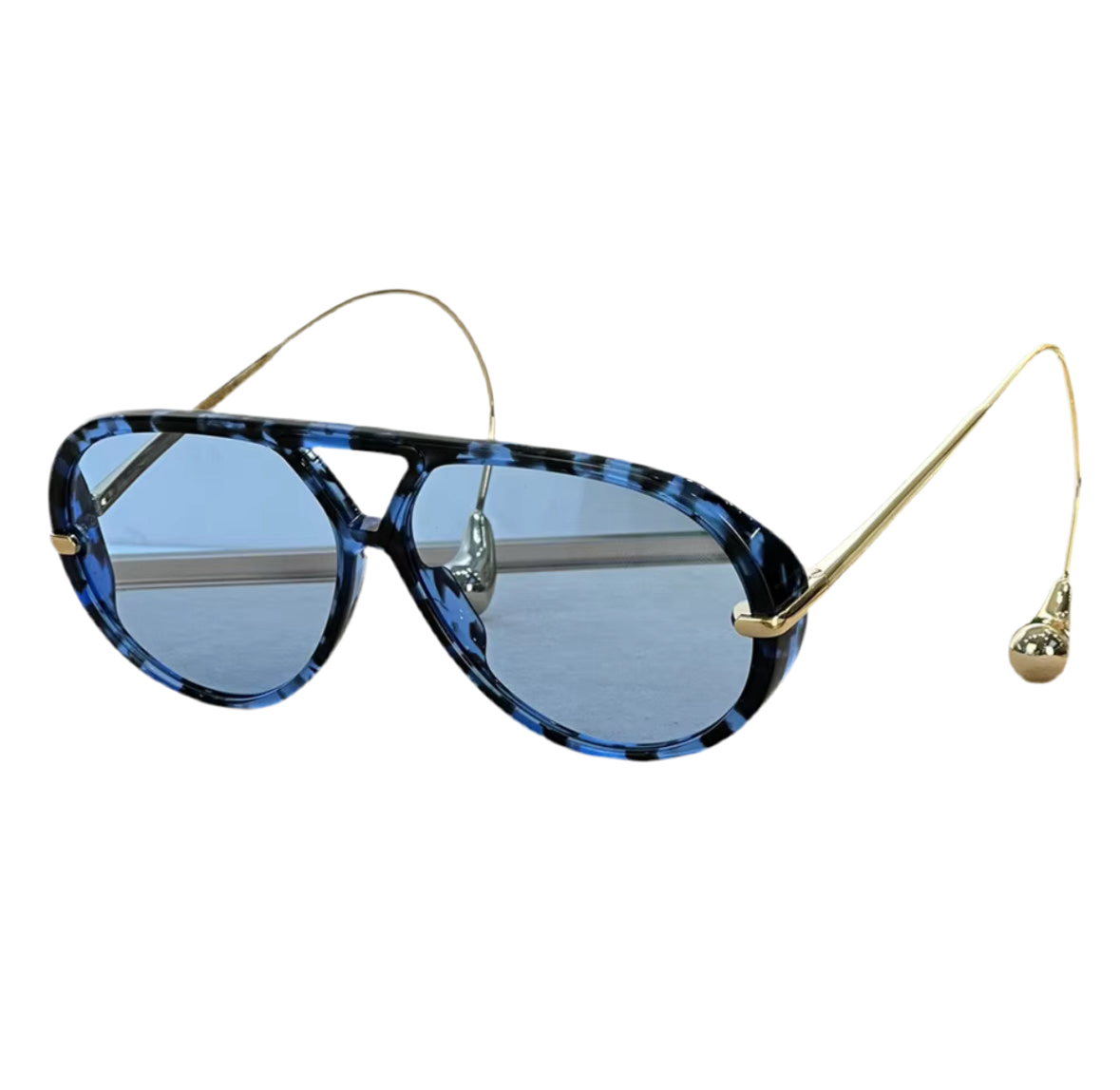 Moderne Sonnenbrille im Statement-Design mit tropfenförmigen Endstücken an goldenen oder silbernen Metallbügeln. Erhältlich in Schwarz, Blau, Braun, Gelb und Schildpatt – stilvoll, auffällig und hochwertig.