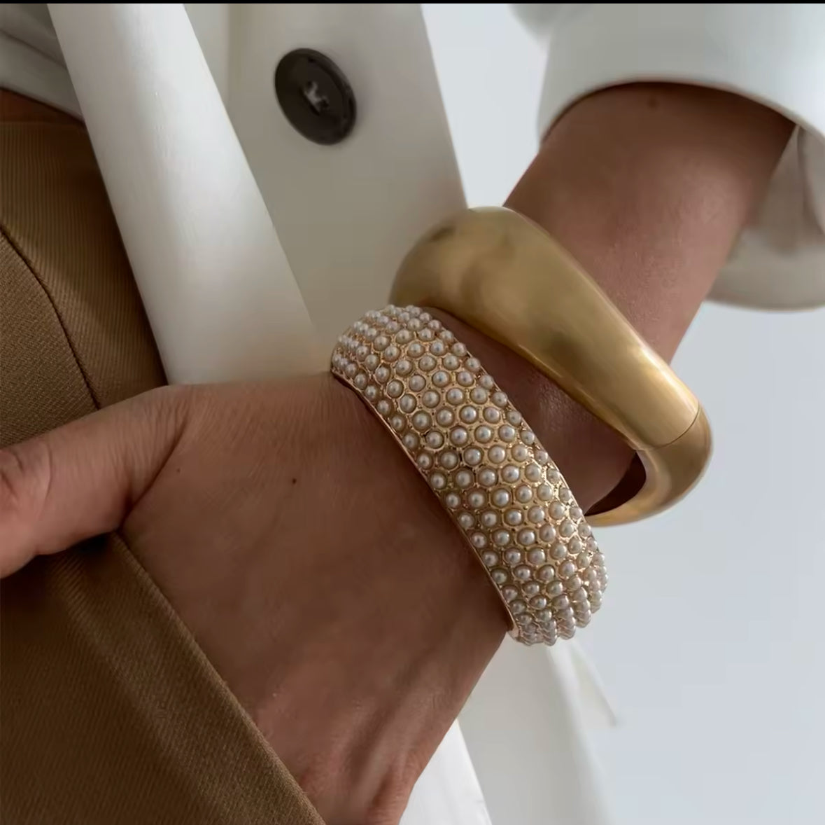 Elegante Armreif-Kombination mit goldener, minimalistischer Manschette und funkelndem Perlenarmband mit durchgehender Besetzung. Luxuriöses Design für stilvolle, moderne Looks, ideal für besondere Anlässe und zeitlose Eleganz.