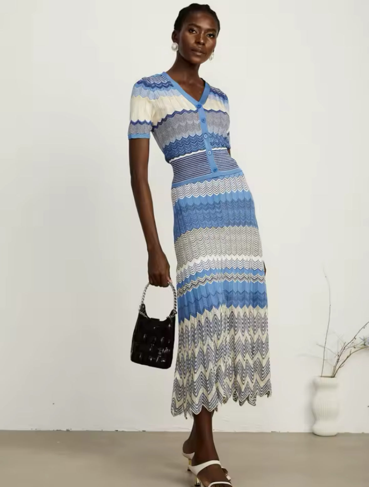 Edles Strick-Midikleid mit V-Ausschnitt, Knopfleiste und kunstvollem Zickzack-Muster in Blautönen. Perfekt für elegante Sommer-Looks.