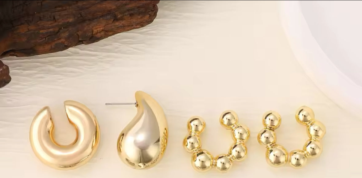 Nahaufnahme eines modernen, mehrteiligen Ear-Cuff-Ohrrings in glänzendem Gold. Das Design kombiniert runde Kugel-Elemente mit geschwungenen Formen, die sich elegant um das Ohr schmiegen. Der auffällige Schmuck verleiht einen futuristischen, luxuriösen Look.