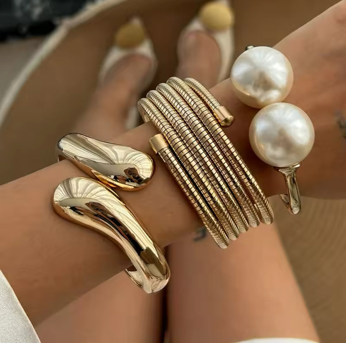 Luxuriöses Armreif-Set in Gold mit strukturierten Armreifen, glänzend geschwungener Armspange und offenem Armreif mit zwei großen Perlen – elegantes Statement-Schmuckstück