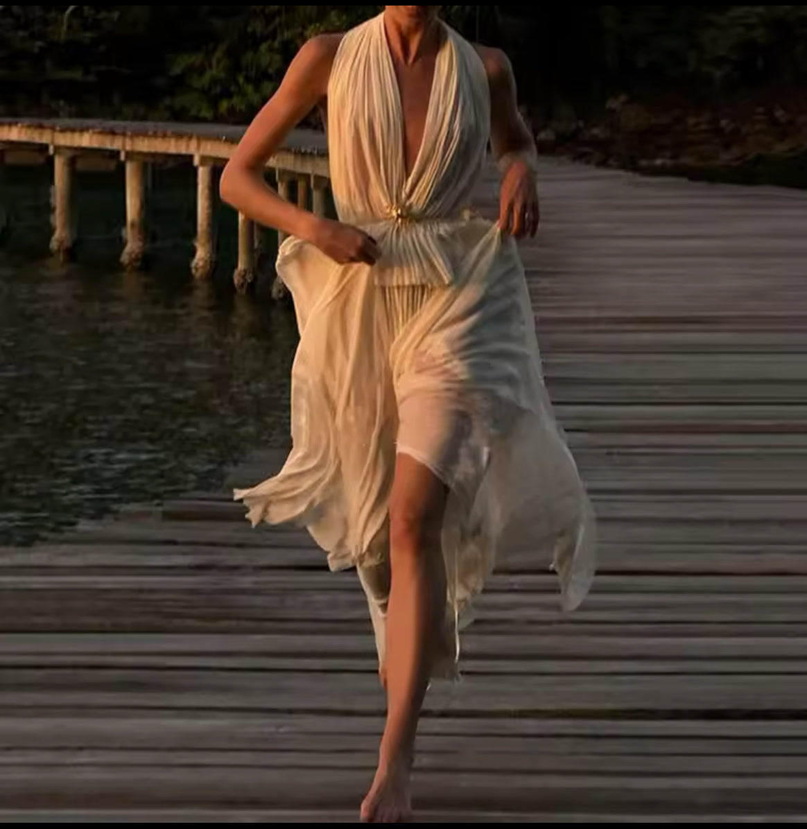 Ein fließendes, cremefarbenes Maxikleid mit tiefem V-Ausschnitt, Neckholder und offenen Rücken. Perfekt für elegante Sommerabende oder besondere Anlässe