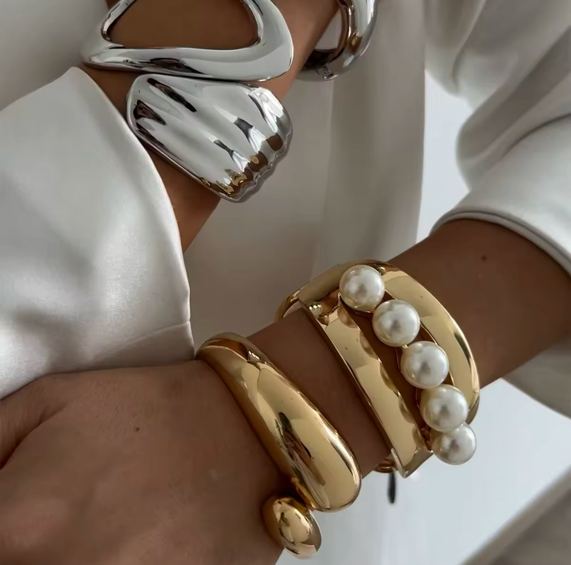 Luxuriöse Statement-Armreifen in Silber und Gold mit skulpturalem Design und Perlen-Details. Avantgardistischer Schmuck mit hochglanzpolierter Oberfläche, ideal für elegante und moderne Looks. Perfekt als exklusives Accessoire für besondere Anlässe.