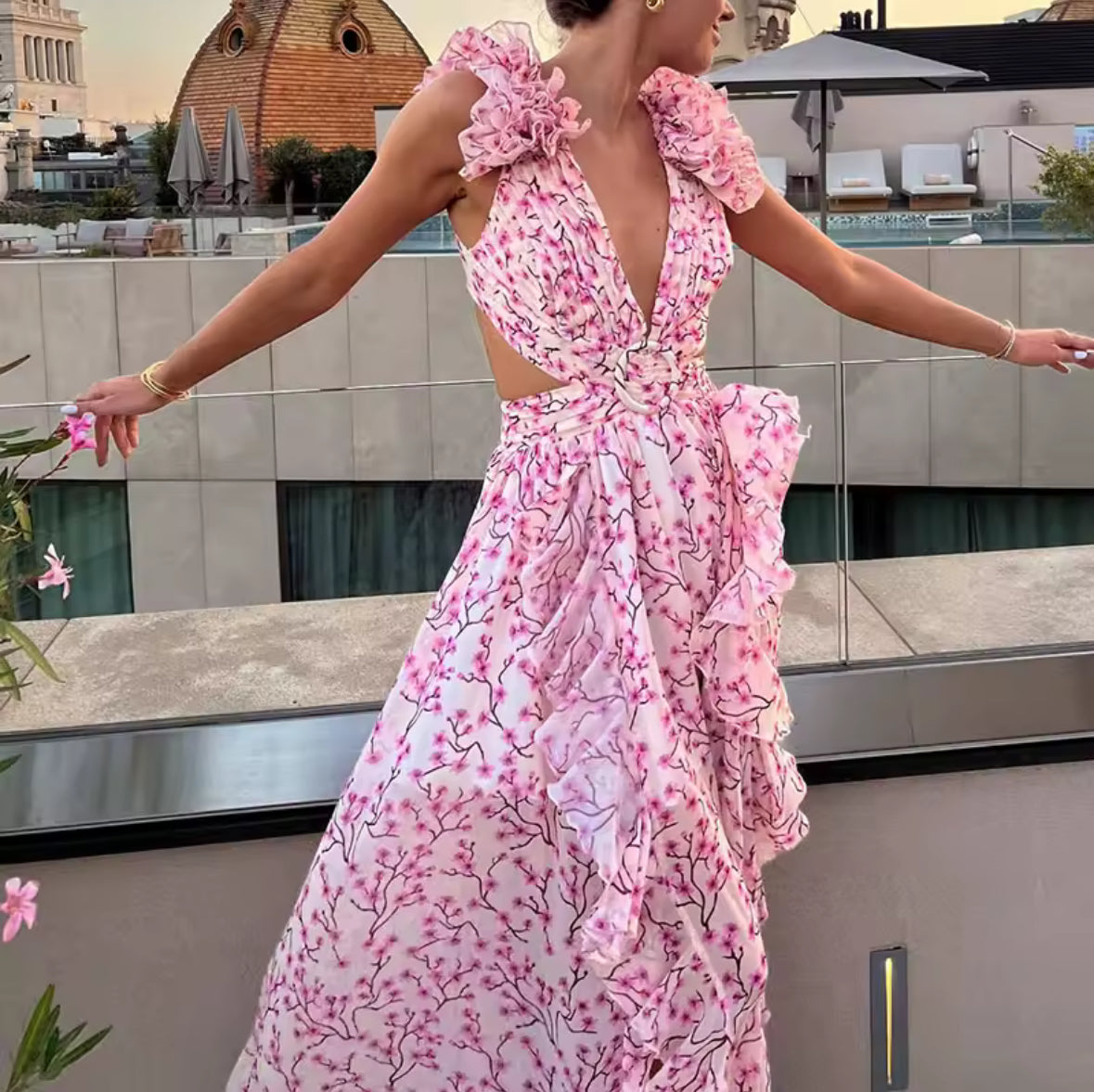 Modell trägt ein elegantes Maxikleid mit Rüschenärmeln, tiefem Ausschnitt, floraler Musterung und Cut-outs an der Taille.