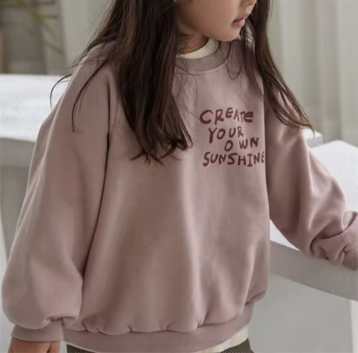 Mädchen trägt das altrosa “Create Your Own Sunshine” Oversized Sweatshirt.