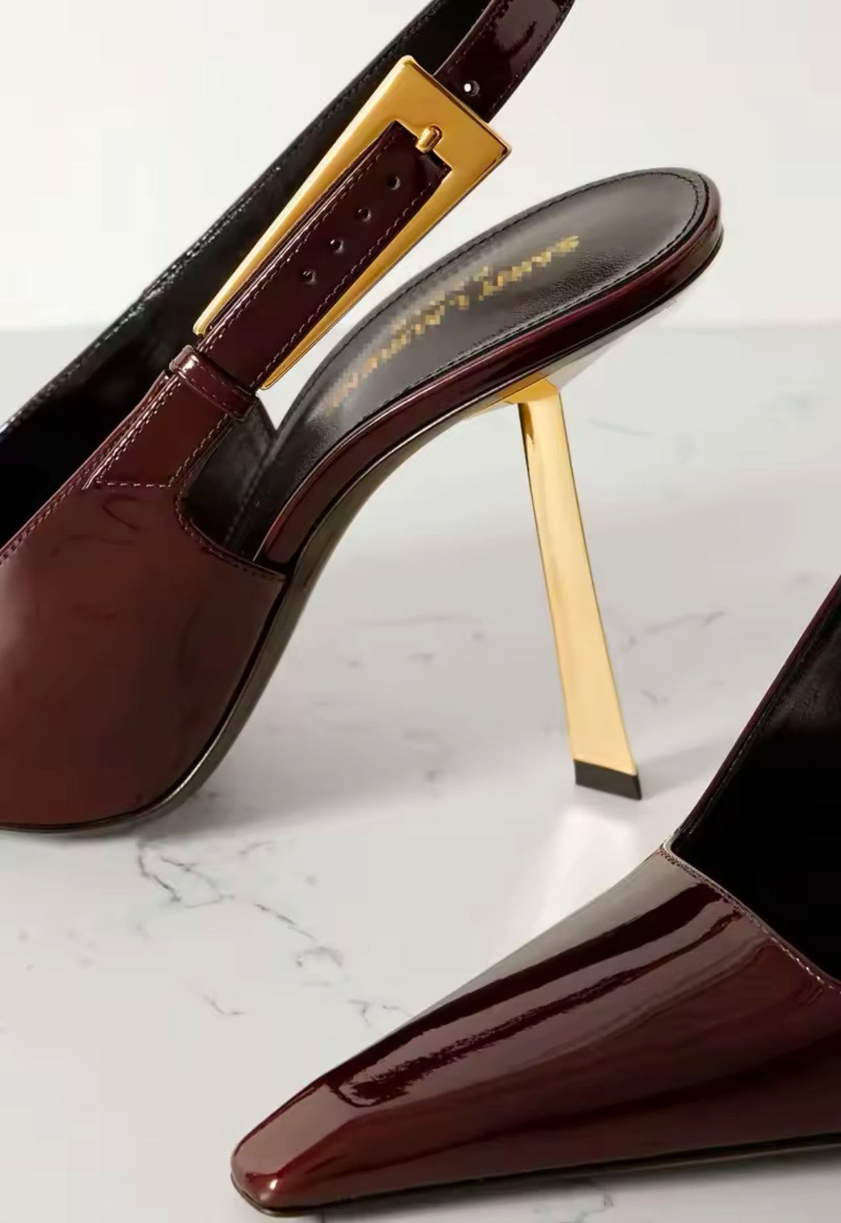 Luxuriöser burgundy-roter Lackleder-Slingback-Pumps mit spitzer Zehenpartie und glänzendem Finish. Der Schuh hat einen schmalen, goldfarbenen Absatz und ein auffälliges geometrisches Metallelement an der Ferse, das für einen modernen und edlen Look sorgt. Perfekt für elegante Outfits mit einem Hauch von Extravaganz.