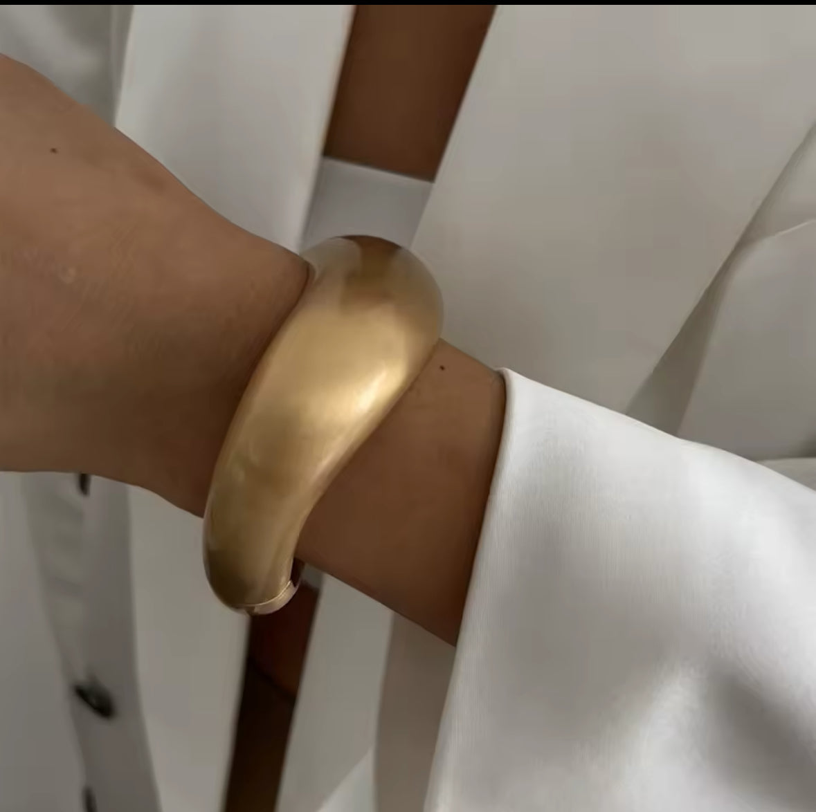 Minimalistischer goldener Armreif mit matter Oberfläche und skulpturaler Form. Modernes, elegantes Design für einen zeitlosen Look. Ein vielseitiges Statement-Schmuckstück für stilvolle und anspruchsvolle Outfits.