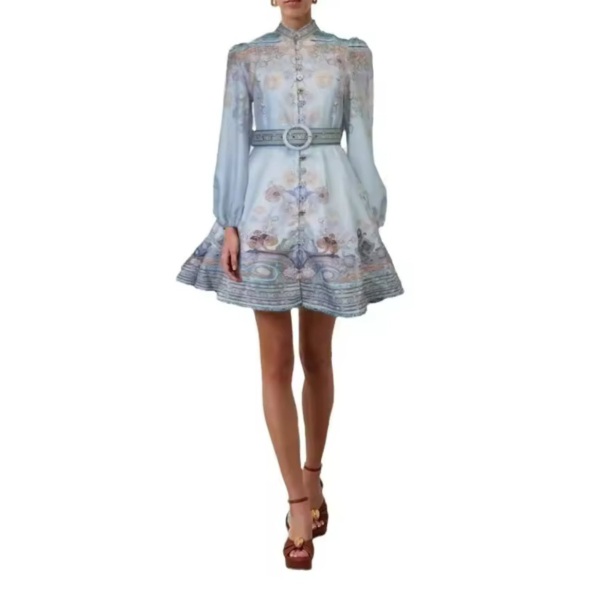 Model trägt ein pastellblaues Minikleid mit hohem Kragen, Knopfleiste, langen transparenten Ärmeln und floralem Muster, kombiniert mit passendem Gürtel