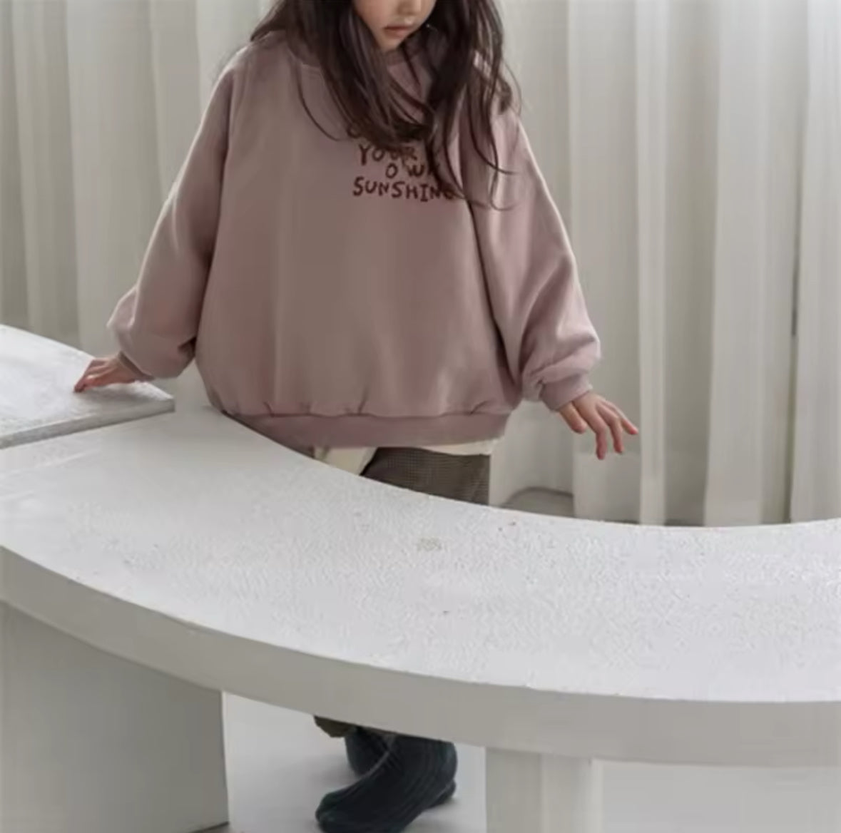 Mädchen trägt das altrosa “Create Your Own Sunshine” Oversized Sweatshirt.