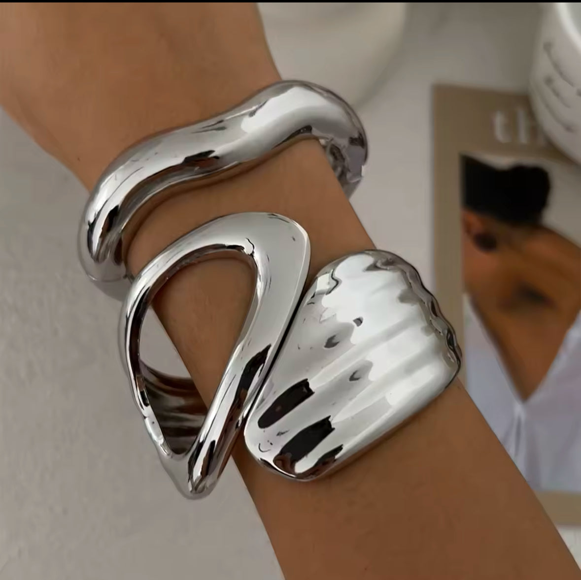 Avantgardistische silberne Armreifen mit organischem, skulpturalem Design und hochglanzpolierter Oberfläche. Modernes Statement-Schmuckstück für elegante, minimalistische und futuristische Looks. Perfekt für exklusive Outfits und besondere Anlässe.