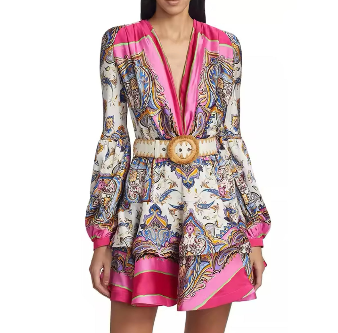Model trägt ein elegantes, kurz geschnittenes Seidenkleid mit buntem Paisley-Muster in Pink und Creme, tailliert mit einem auffälligen goldenen Gürtel, perfekt für City-Chic und besondere Anlässe.