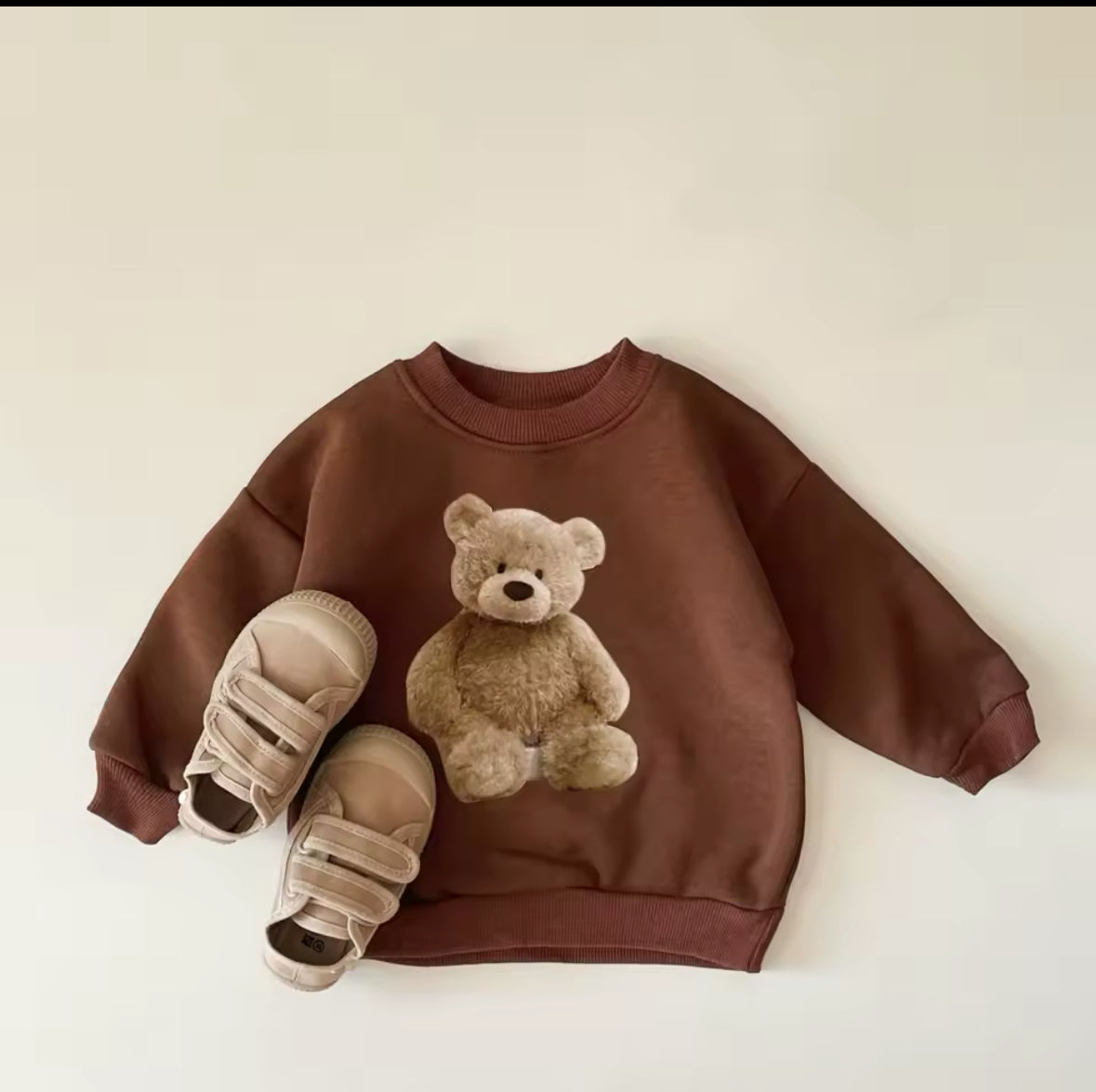 Braunes Sweatshirt mit Teddy-Motiv, kombiniert mit Sneakern.