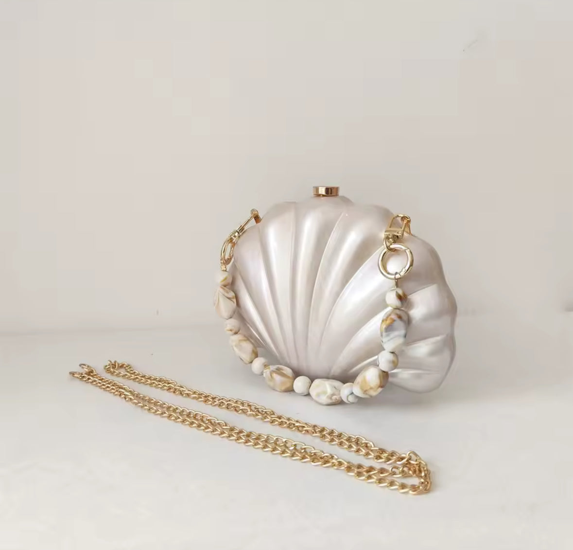 Shell Clutch mit goldfarbenem Verschluss und marmorierter Perlenkette