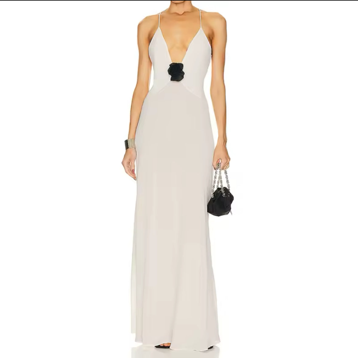 Rückenfreies Maxikleid mit zarten Spaghettiträgern und kontrastierender Rosenapplikation auf der Taille, in Schwarz und Ivory erhältlich. Elegantes Design mit fließendem Stoff und figurbetontem Schnitt.