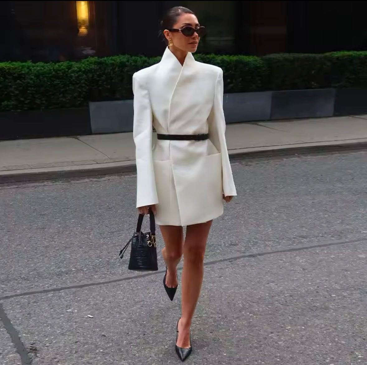 Elegantes Blazerkleid in Cremeweiß mit minimalistischer Silhouette und strukturiertem Kragen. Tailliert mit einem schwarzen Gürtel für eine feminine, moderne Passform. Kombiniert mit schwarzen High Heels und edler Handtasche – perfekter Power-Look für Business und Events.
