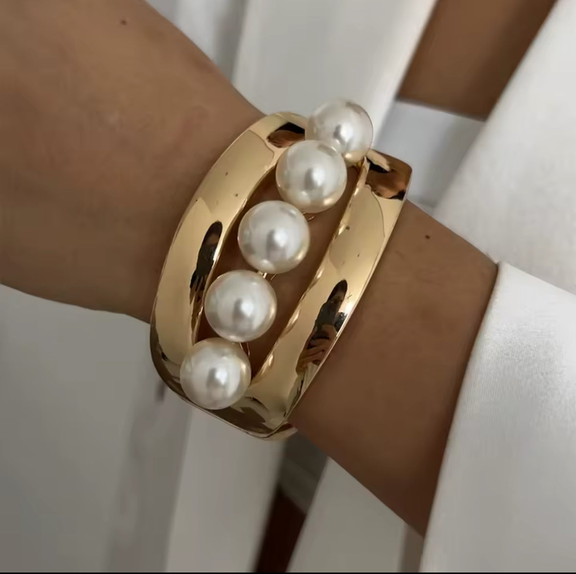 Eleganter goldener Armreif mit offenem Cut-Out-Design und fünf großen Perlen als luxuriösem Highlight. Zeitloses Schmuckstück für einen stilvollen, femininen Look. Perfekt für besondere Anlässe, Abendmode und moderne Eleganz.