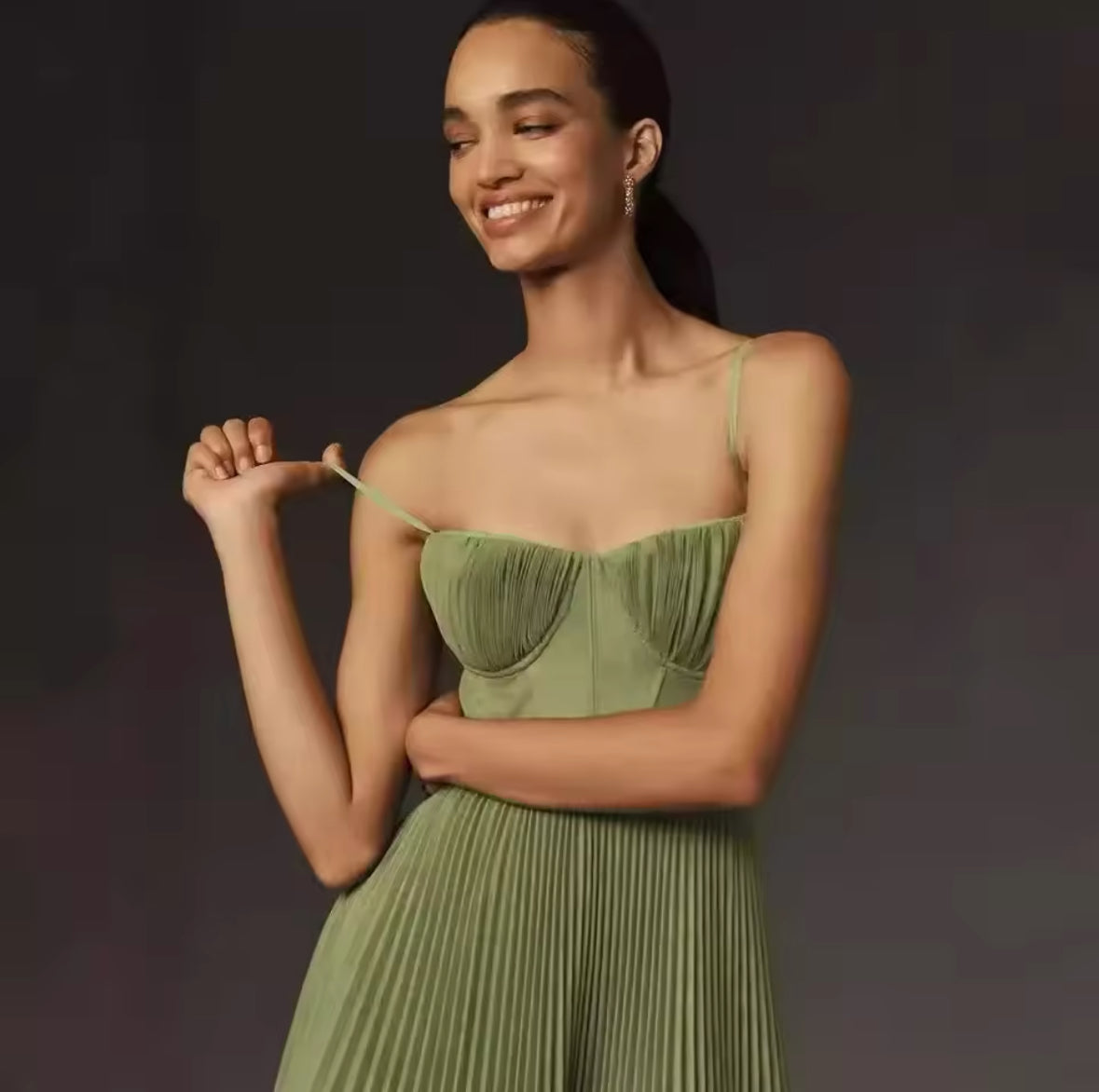 Ein elegantes, fließendes Midikleid in sanftem Olivgrün mit plissiertem Rock und feinen Trägern, ideal für feminine und stilvolle Looks.