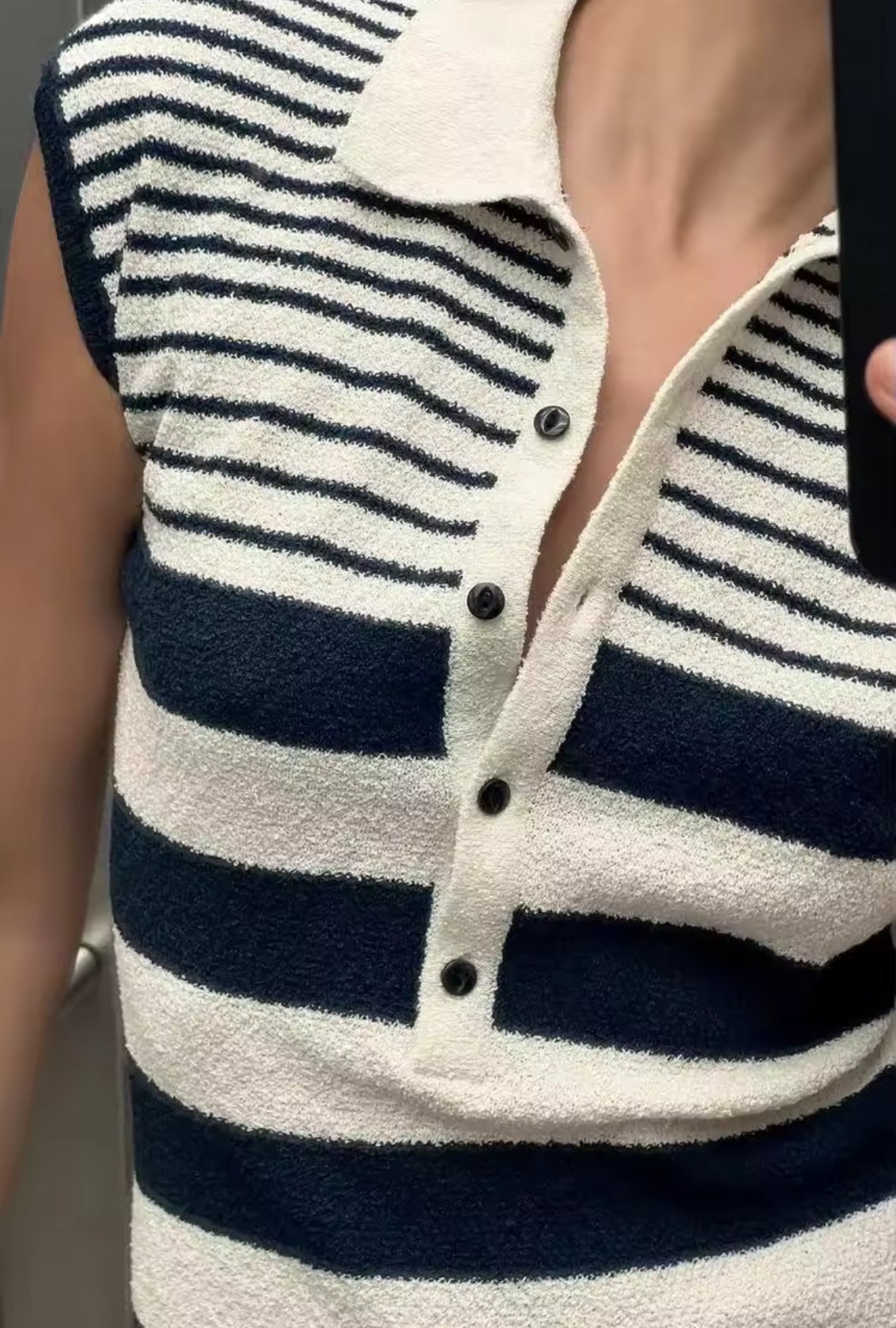 Ärmelloses, figurbetontes Minikleid mit navyblauen und cremeweißen Streifen, Polokragen und Knopfleiste aus strukturiertem Strickstoff – aufgenommen als Spiegelselfie in einem Aufzug.