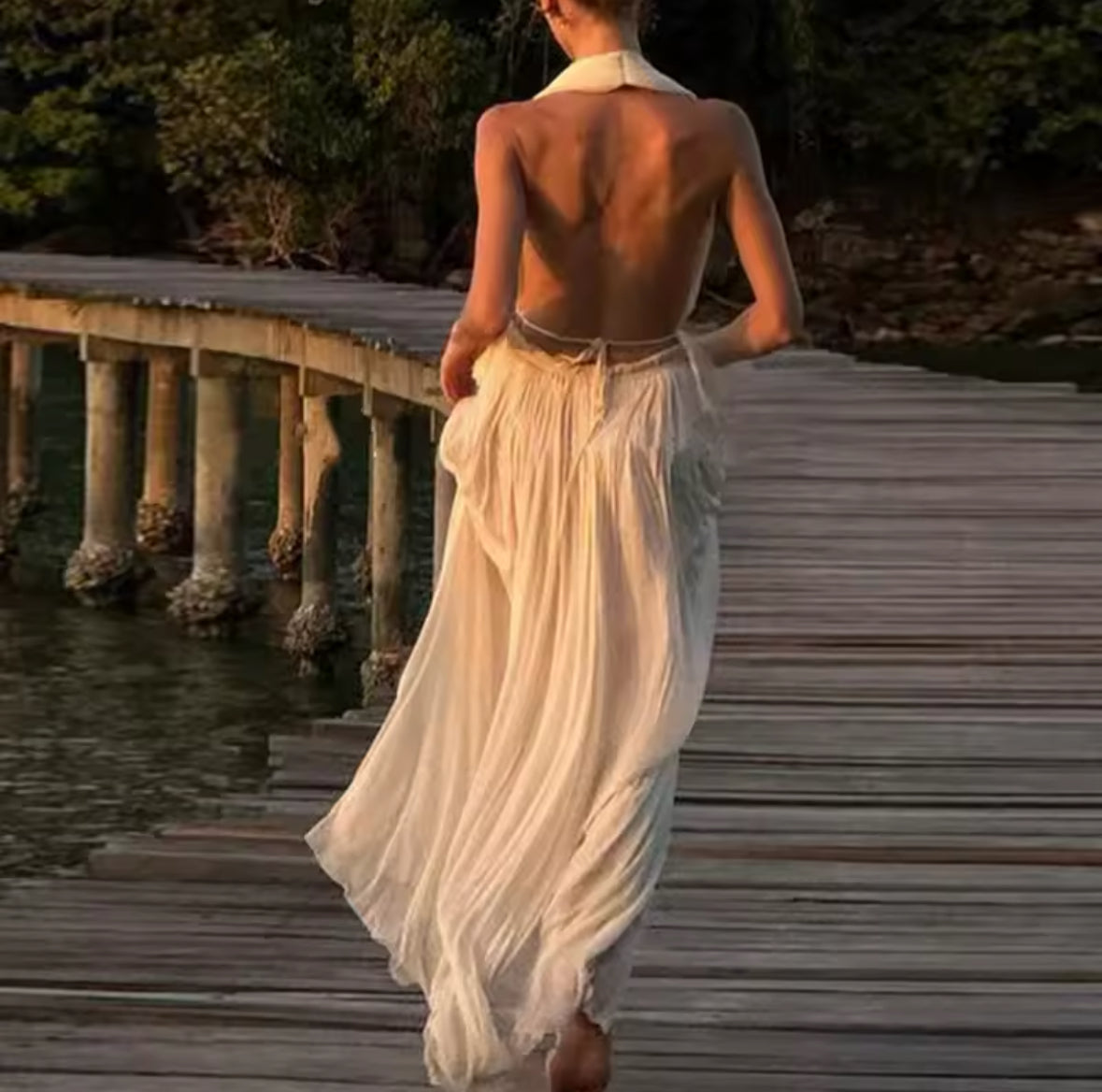 Ein fließendes, cremefarbenes Maxikleid mit tiefem V-Ausschnitt, Neckholder und offenen Rücken. Perfekt für elegante Sommerabende oder besondere Anlässe