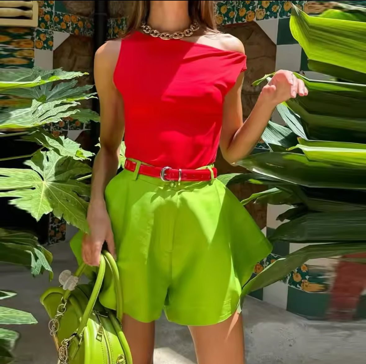 grüne Satin-Shorts mit High-Waist-Design, kombiniert mit einer auffälligen gelben Bluse und Statement-Ohrringen für einen sommerlichen Trend-Look.