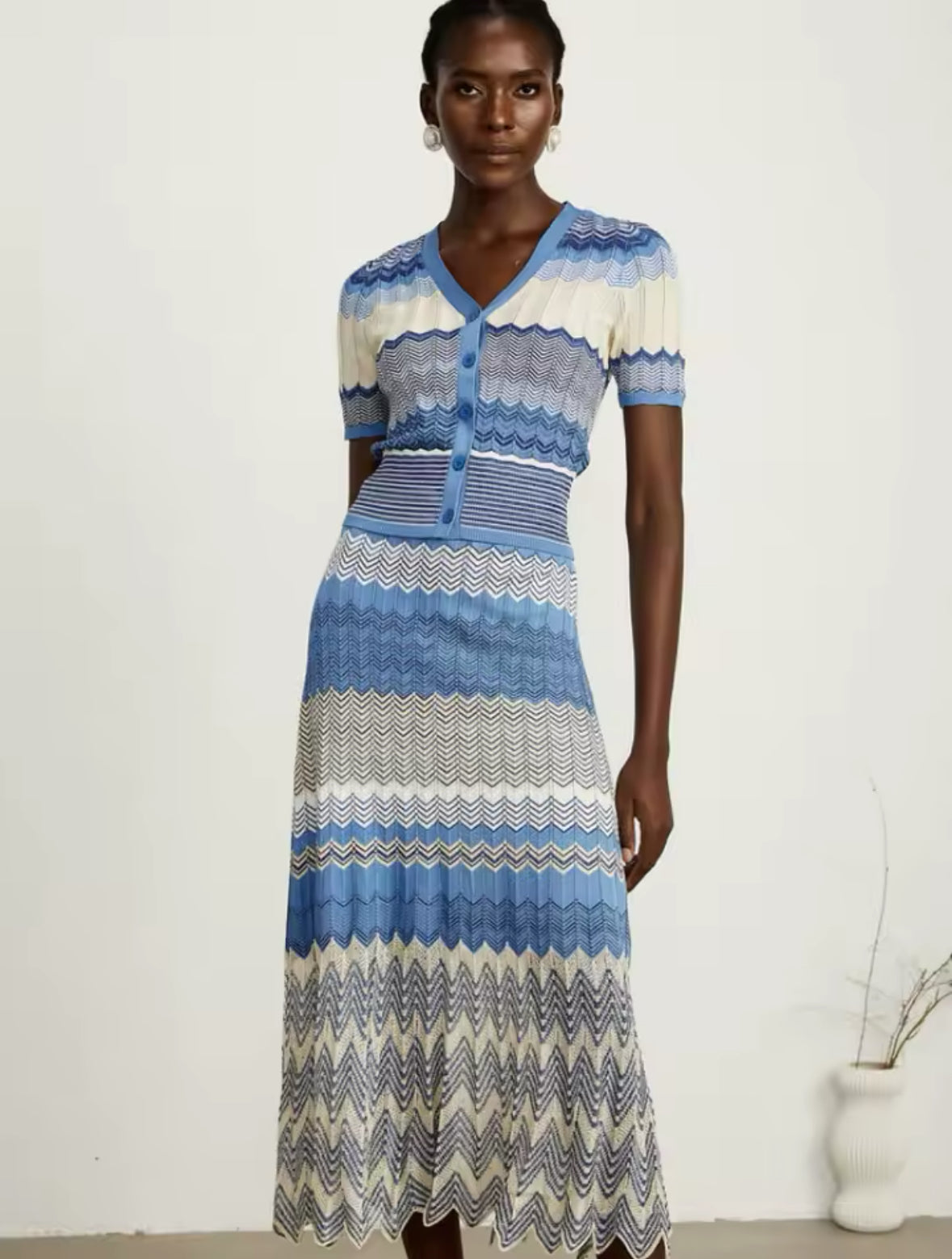 Edles Strick-Midikleid mit V-Ausschnitt, Knopfleiste und kunstvollem Zickzack-Muster in Blautönen. Perfekt für elegante Sommer-Looks.