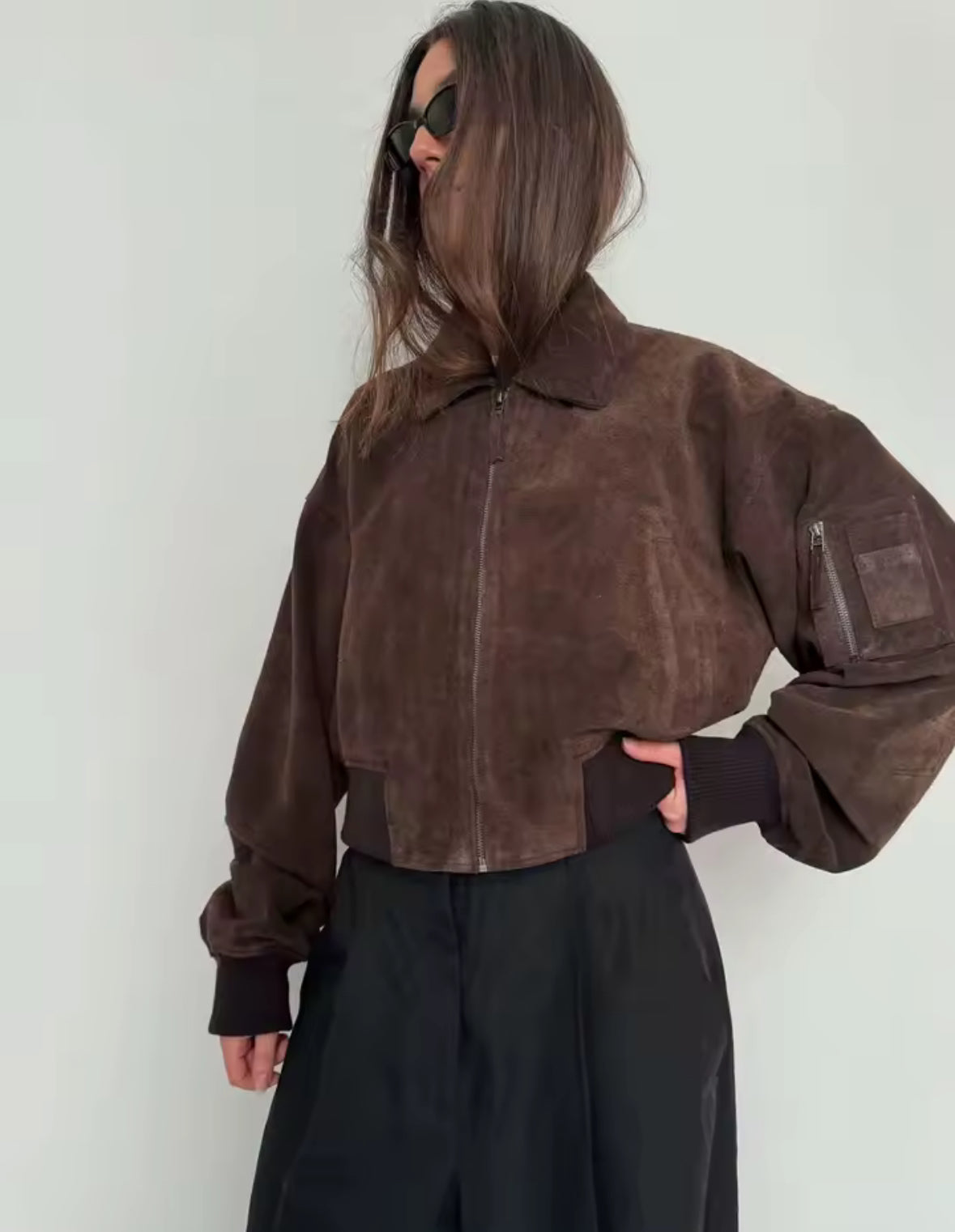 Raya Bomber Jacket – Oversized Bomberjacke in Wildleder-Optik mit Reißverschluss, Armtasche und elastischen Bündchen, erhältlich in Braun und Schwarz.