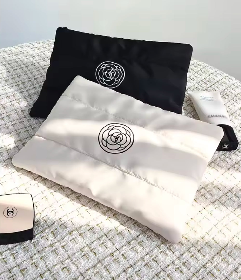 Zwei stilvolle Kosmetiktaschen in Schwarz und Creme mit wattierter Oberfläche und einem minimalistischen Rosen-Logo. Perfekt für die Aufbewahrung von Make-up und Pflegeprodukten unterwegs.