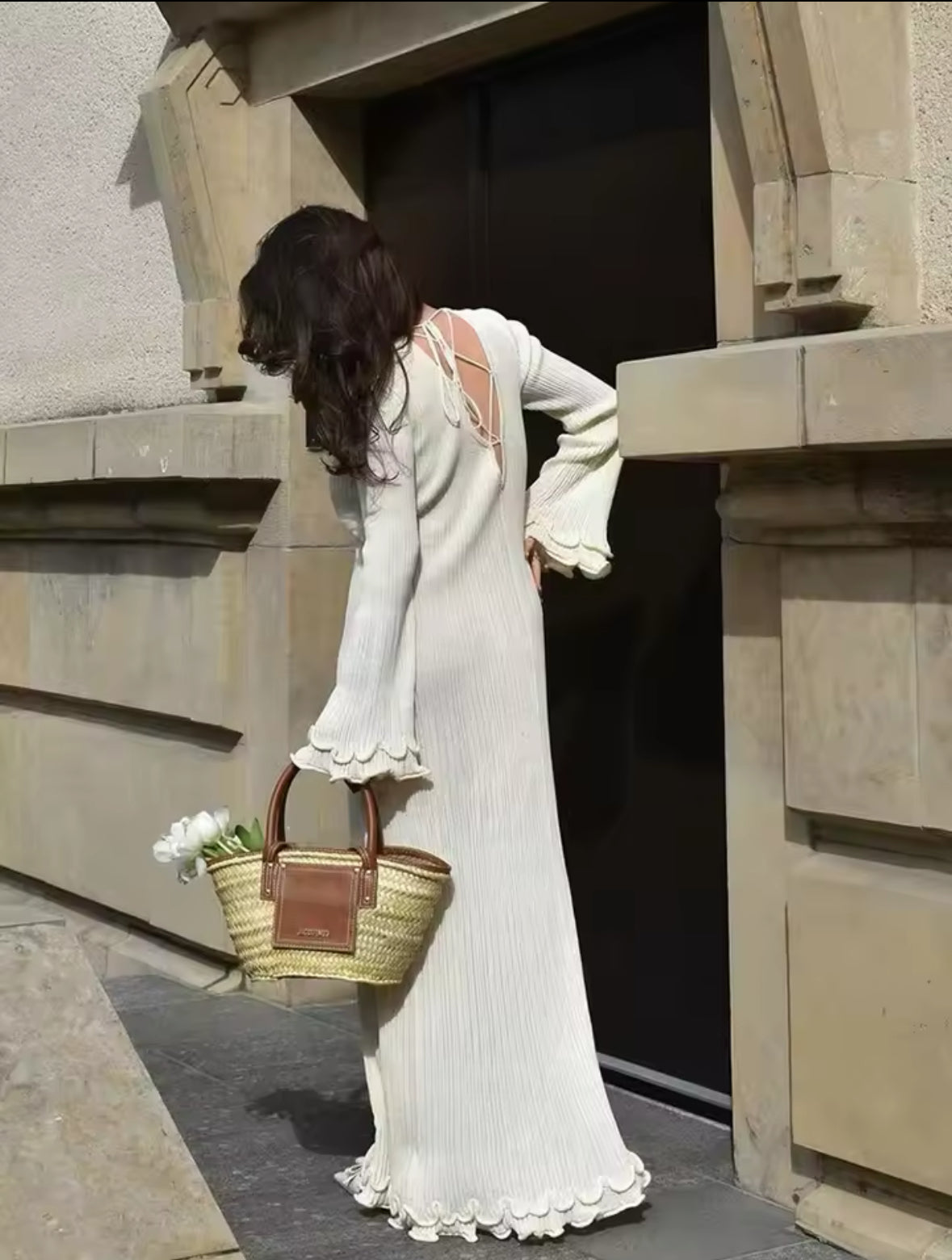 Elegantes Maxikleid in Cremeweiß mit verspieltem Rückendetail und Schnürung. Weit geschnittene Ärmel und wellenförmige Säume für einen romantischen, femininen Look. Kombiniert mit einer edlen Strohtasche – perfekt für stilvolle Sommer- und Frühlings-Outfits.