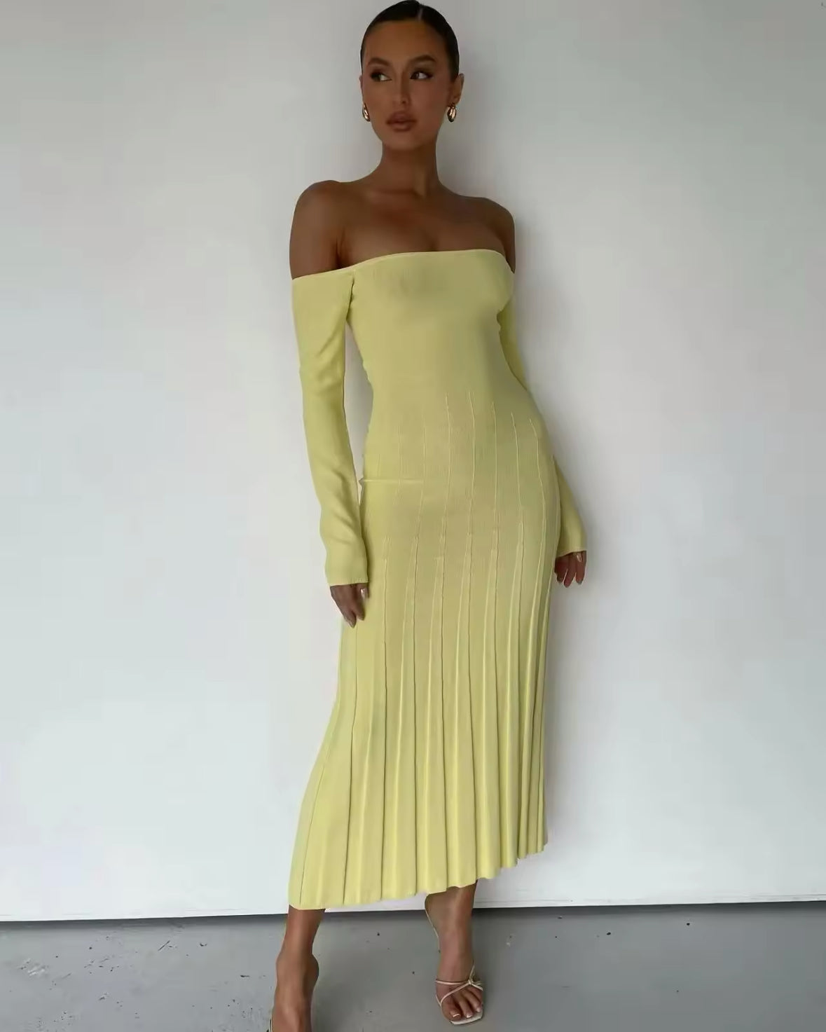 Model trägt ein schulterfreies, langärmeliges Midikleid in softem Gelb,