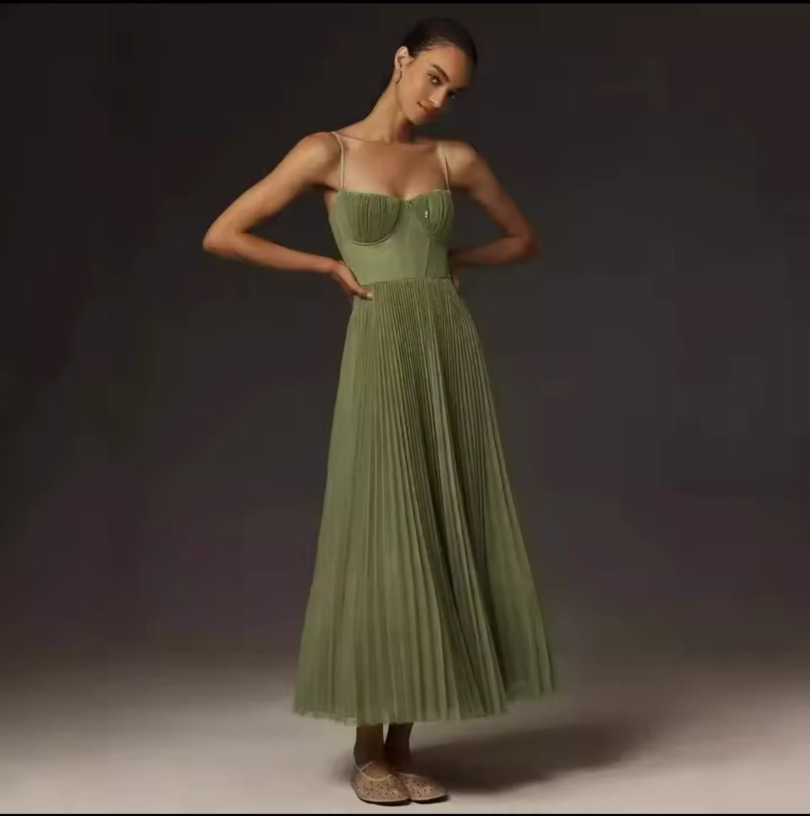 Ein elegantes, fließendes Midikleid in sanftem Olivgrün mit plissiertem Rock und feinen Trägern, ideal für feminine und stilvolle Looks.