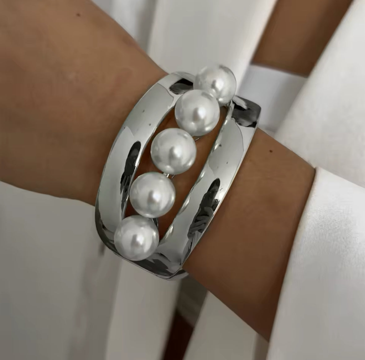 Eleganter silberner Armreif mit offenem Cut-Out-Design und fünf großen Perlen als luxuriösem Highlight. Zeitloses Schmuckstück für einen stilvollen, femininen Look. Perfekt für besondere Anlässe, Abendmode und moderne Eleganz.
