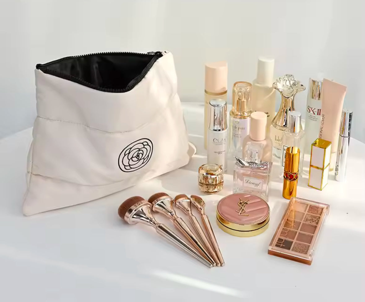 Zwei stilvolle Kosmetiktaschen in Schwarz und Creme mit wattierter Oberfläche und einem minimalistischen Rosen-Logo. Perfekt für die Aufbewahrung von Make-up und Pflegeprodukten unterwegs.