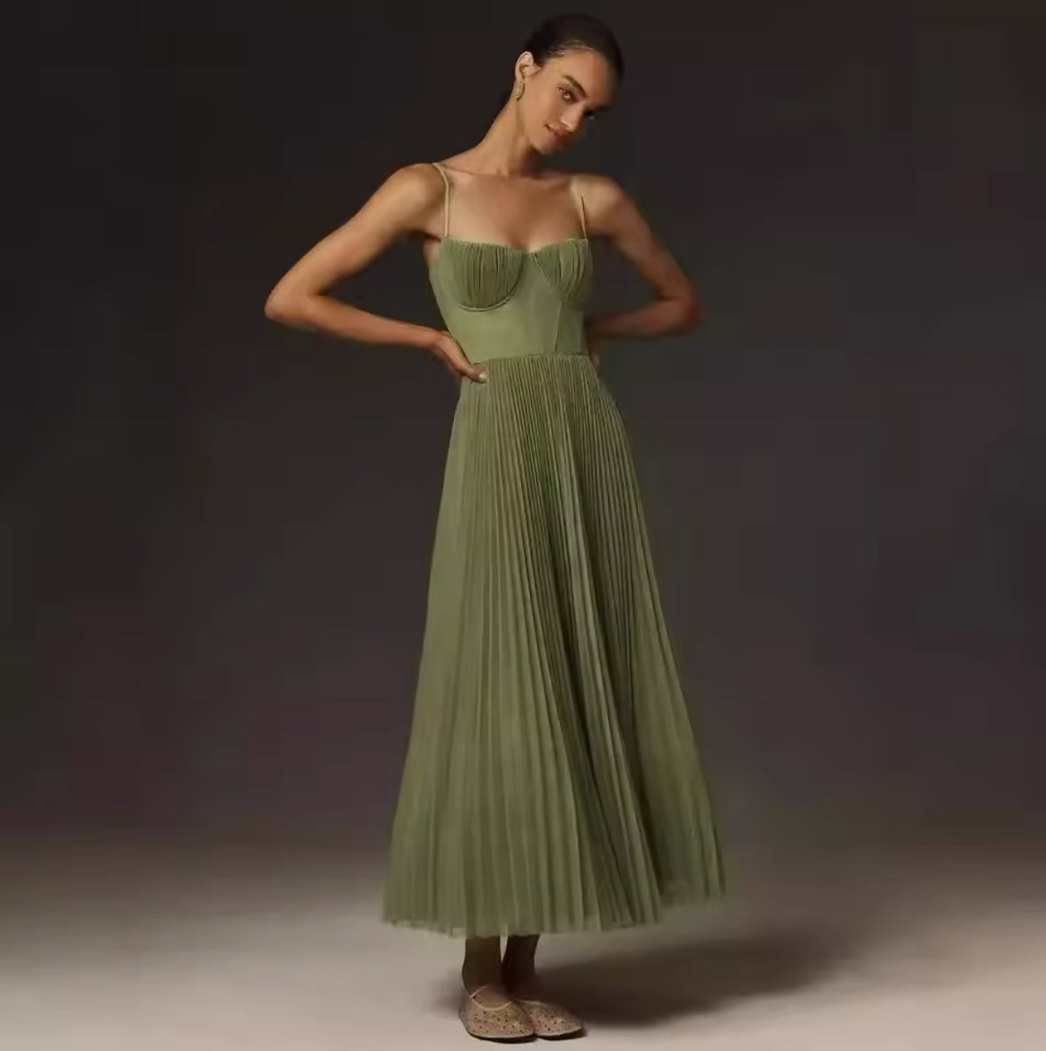 Ein elegantes, fließendes Midikleid in sanftem Olivgrün mit plissiertem Rock und feinen Trägern, ideal für feminine und stilvolle Looks.