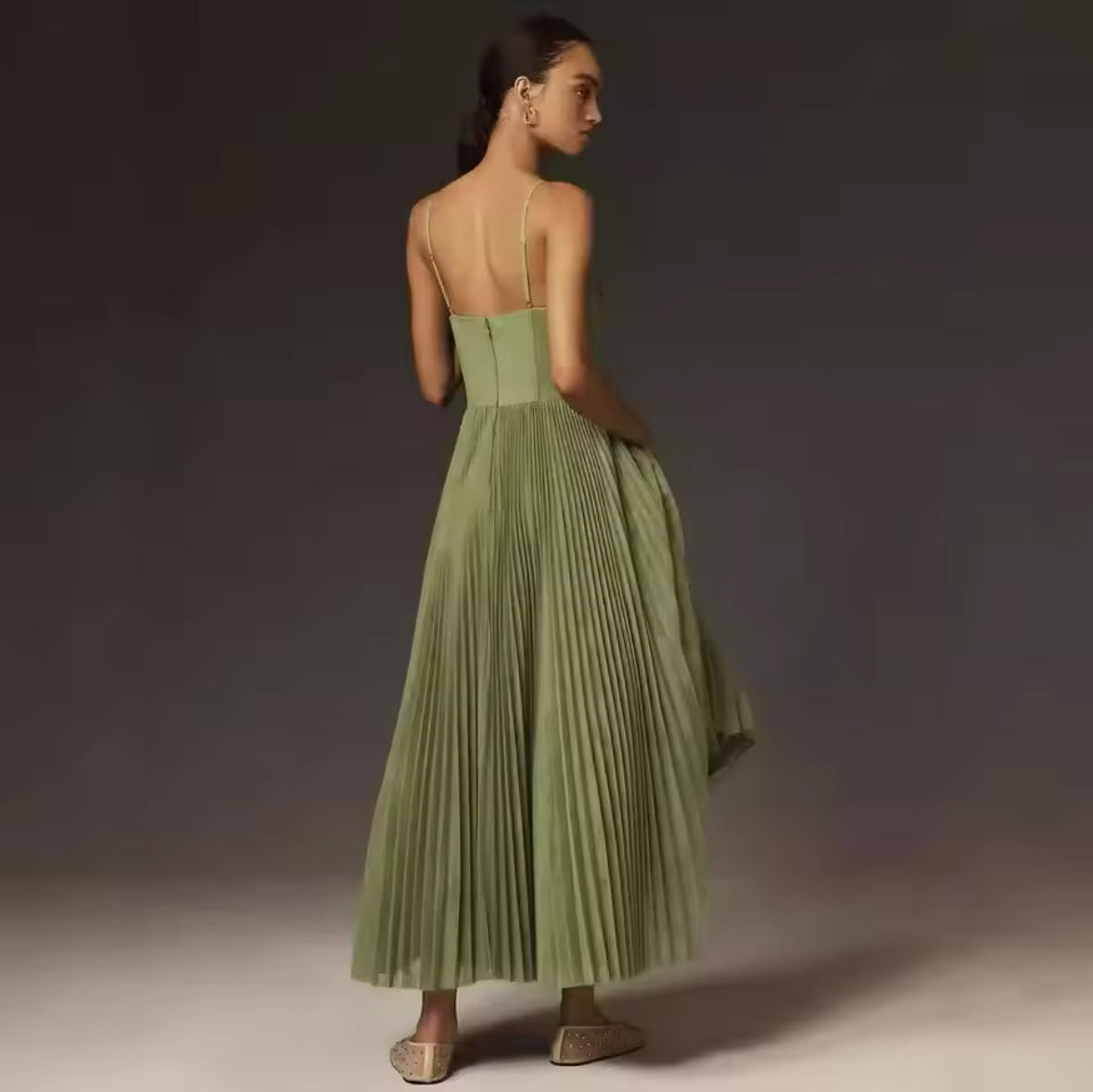 Ein elegantes, fließendes Midikleid in sanftem Olivgrün mit plissiertem Rock und feinen Trägern, ideal für feminine und stilvolle Looks.