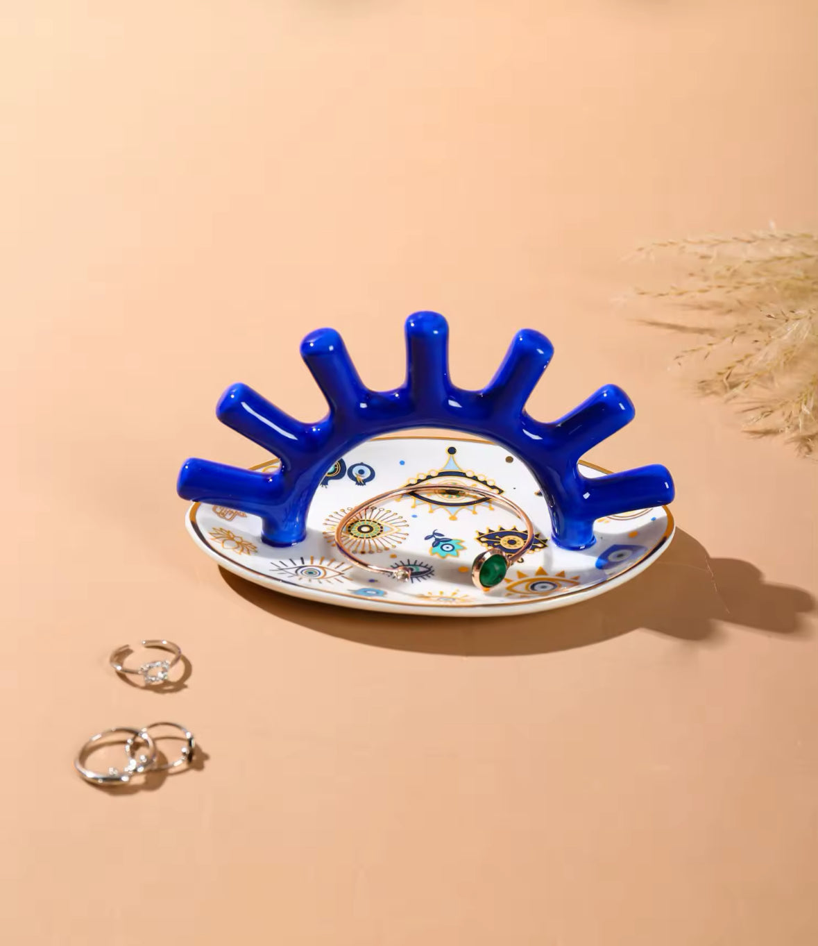 Blauer Schmuckhalter mit wenigen Schmuckstücken auf verzierter Ablage.
