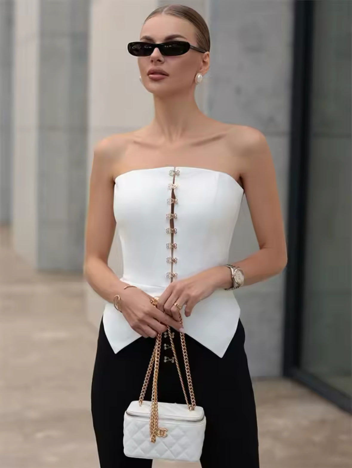 Elegantes weißes Korsett-Top mit goldenen Haken-Details, kombiniert mit schwarzer High-Waist-Hose für einen modernen und stilvollen Look.