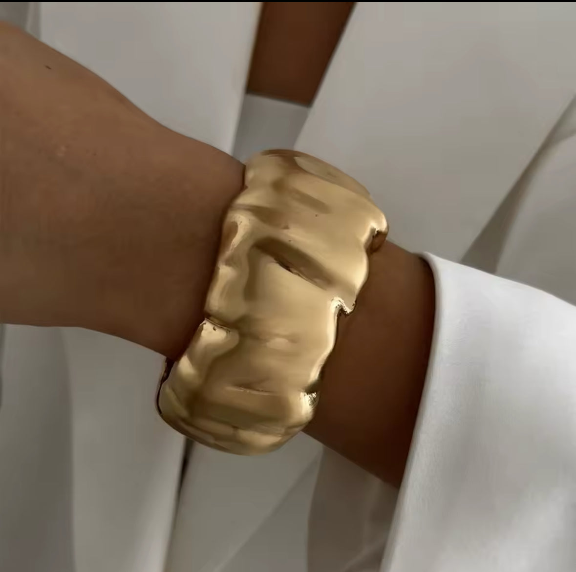 Skulpturaler goldener Armreif mit strukturierter, unregelmäßiger Oberfläche. Modernes und einzigartiges Design für einen avantgardistischen Look. Perfekt als Statement-Schmuckstück für stilvolle und minimalistische Outfits.