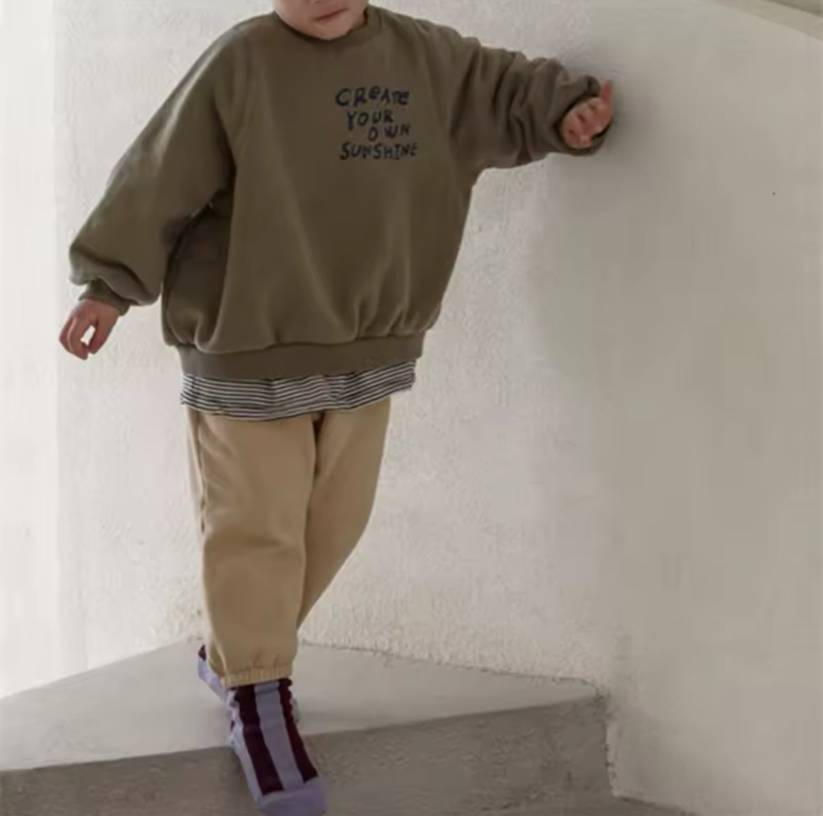 Junge mit olivgrünem Oversized Sweatshirt und motivierendem Print