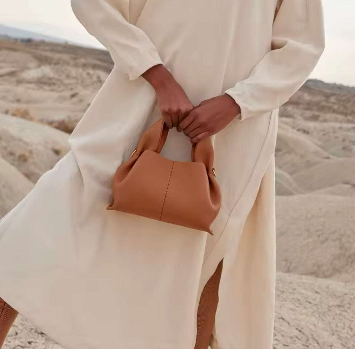 Minimalistische, weiche Handtasche aus hochwertigem veganes Leder mit elegantem, geschwungenem Design. Verfügbar in den Farben Elfenbein, Schwarz, Camel und Taupe – perfekt für einen modernen und zeitlosen Look.