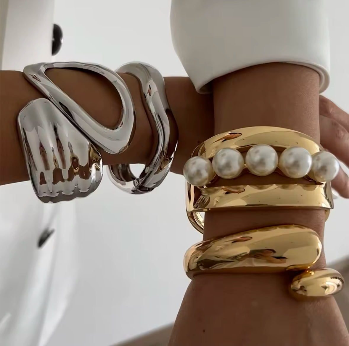 Luxuriöse Statement-Armreifen in Silber und Gold mit skulpturalem Design und Perlen-Details. Avantgardistischer Schmuck mit hochglanzpolierter Oberfläche, ideal für elegante und moderne Looks. Perfekt als exklusives Accessoire für besondere Anlässe.