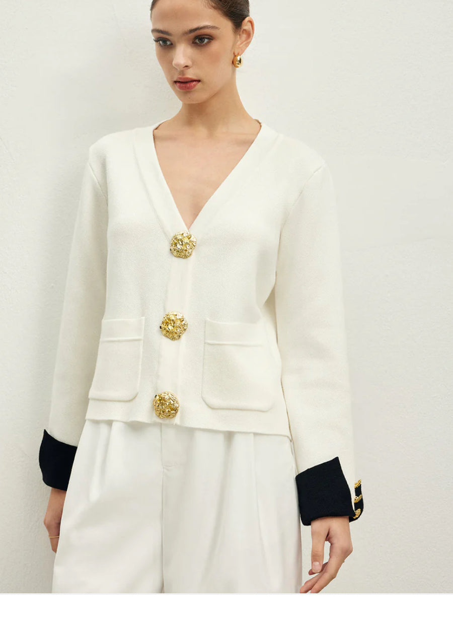Eleganter schwarzer und weißer Cardigan mit V-Ausschnitt, goldenen Zierknöpfen und kontrastierenden Ärmelabschlüssen. Ein luxuriöses Statement-Piece für stilvolle Outfits.