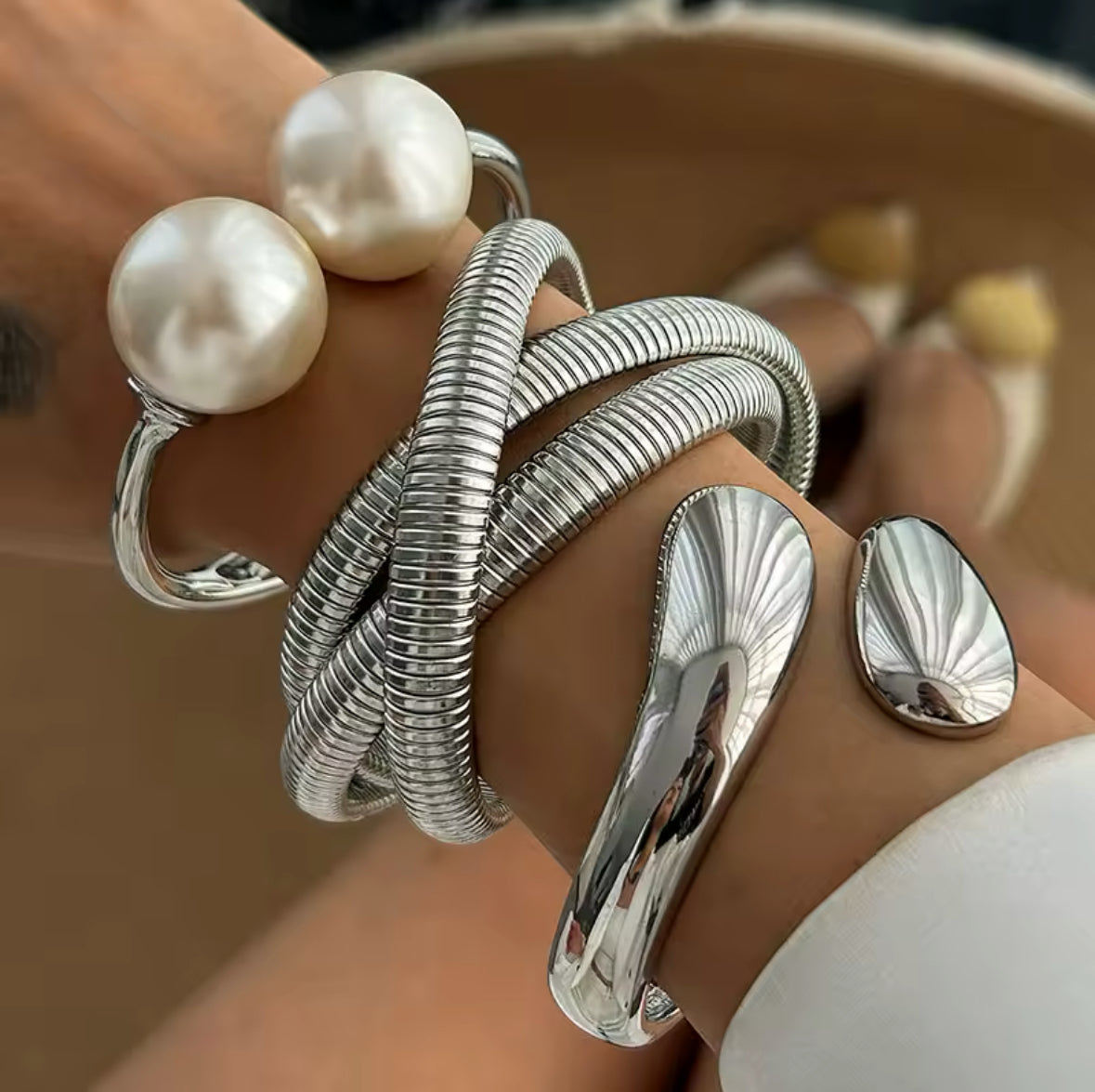 Elegantes Armreif-Set in Silber mit mehreren strukturierten Armreifen, offener Spange mit Perlen und glänzend geformtem Armreif – moderner, minimalistischer Statement-Schmuck.