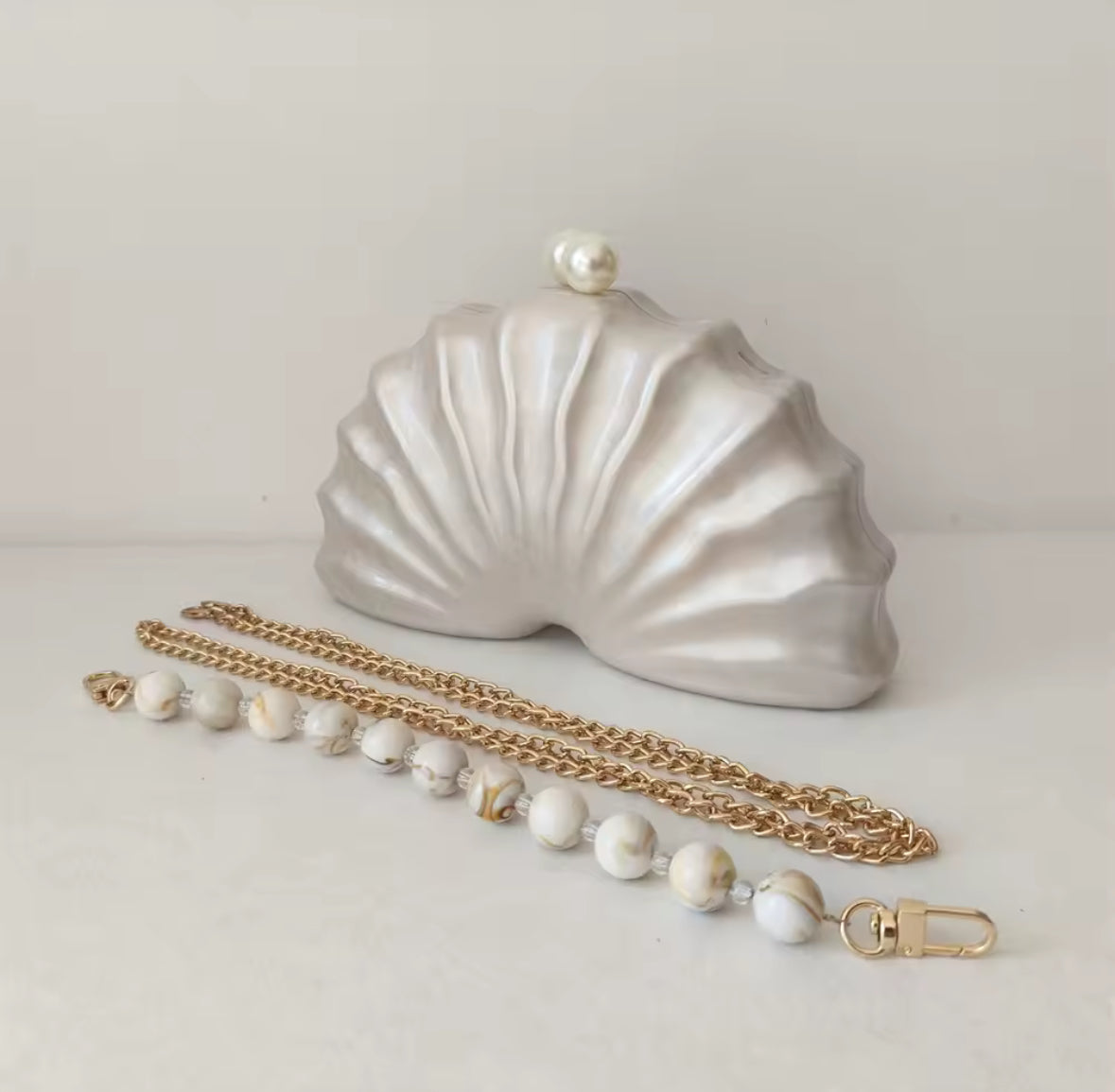Muschelförmige Clutch mit Perlenkette und Goldkette