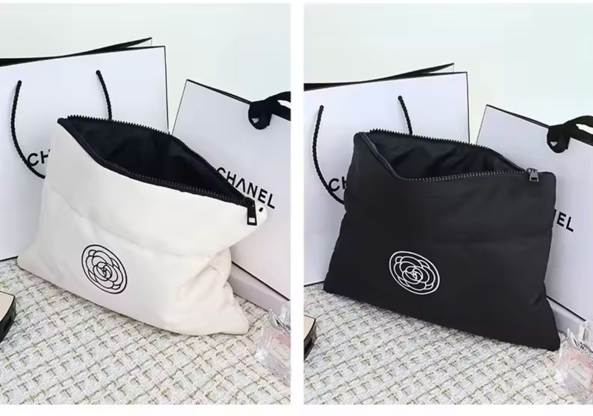 Zwei stilvolle Kosmetiktaschen in Schwarz und Creme mit wattierter Oberfläche und einem minimalistischen Rosen-Logo. Perfekt für die Aufbewahrung von Make-up und Pflegeprodukten unterwegs.
