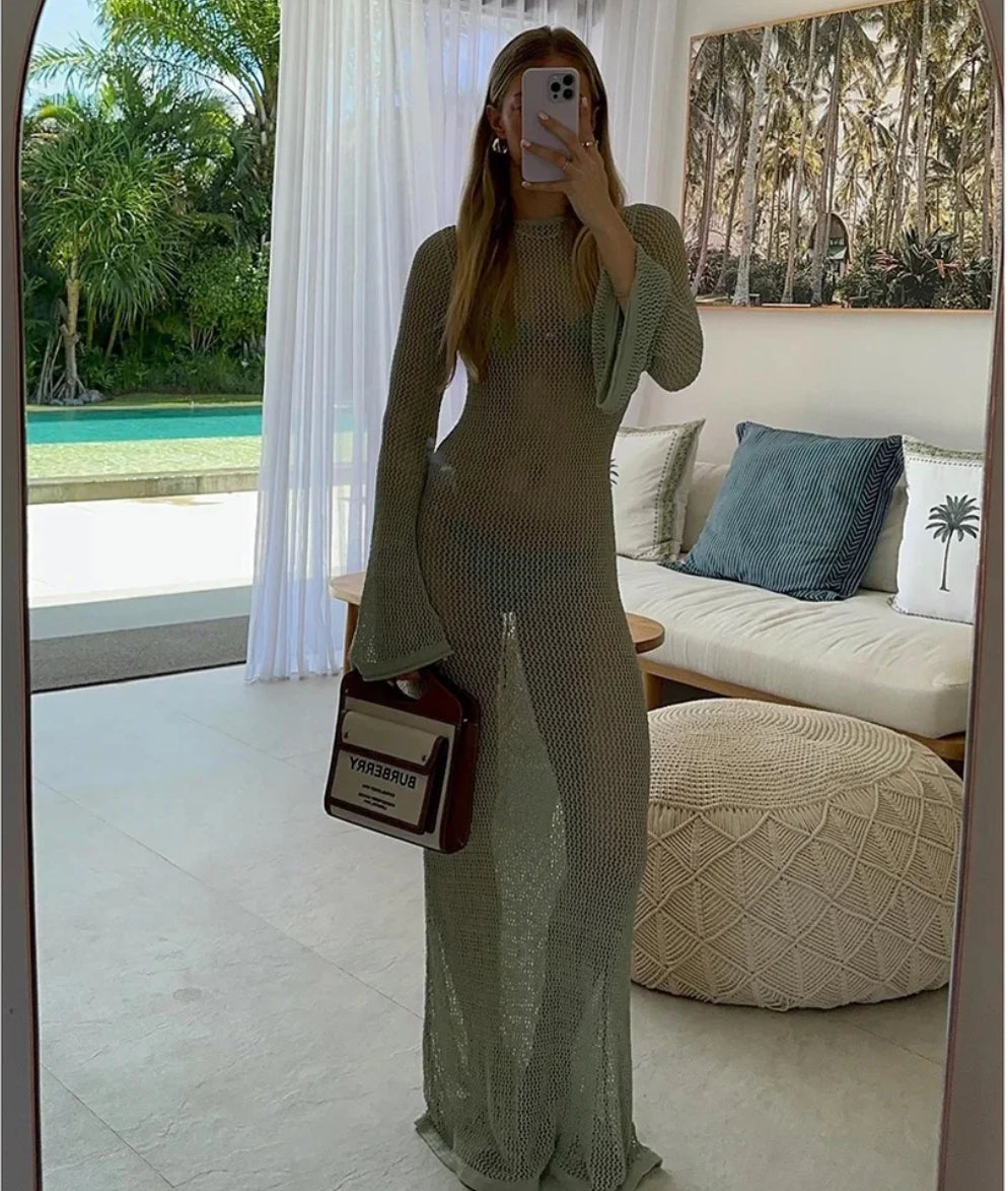 Frau trägt ein langes, transparentes Netzkleid mit tiefem Rückenausschnitt am Strand/in der Sonne