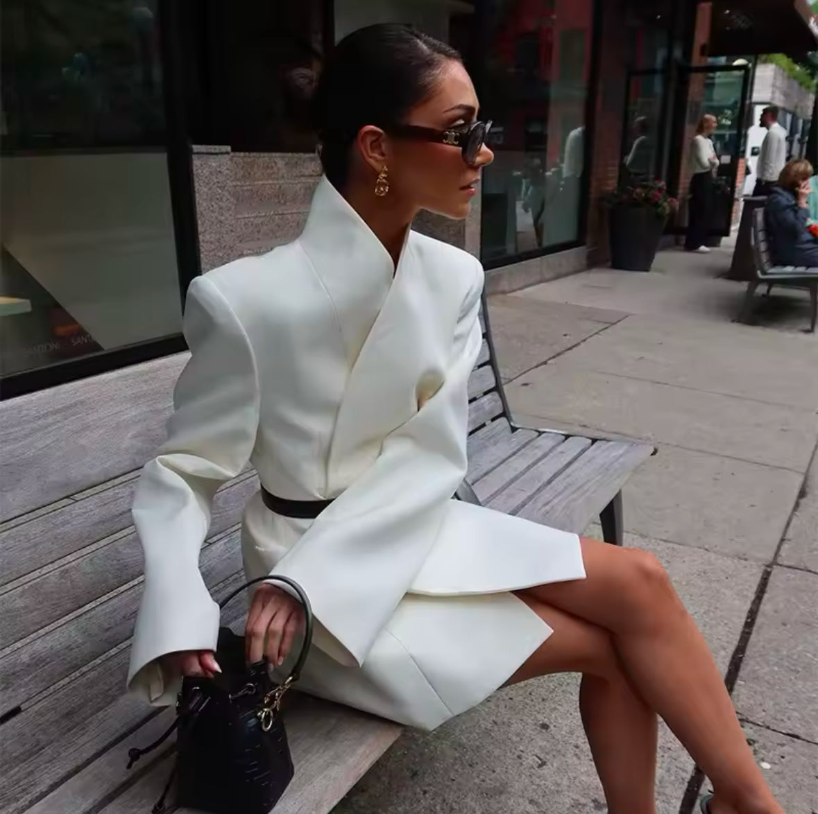 Elegantes Blazerkleid in Cremeweiß mit minimalistischer Silhouette und strukturiertem Kragen. Tailliert mit einem schwarzen Gürtel für eine feminine, moderne Passform. Kombiniert mit schwarzen High Heels und edler Handtasche – perfekter Power-Look für Business und Events.