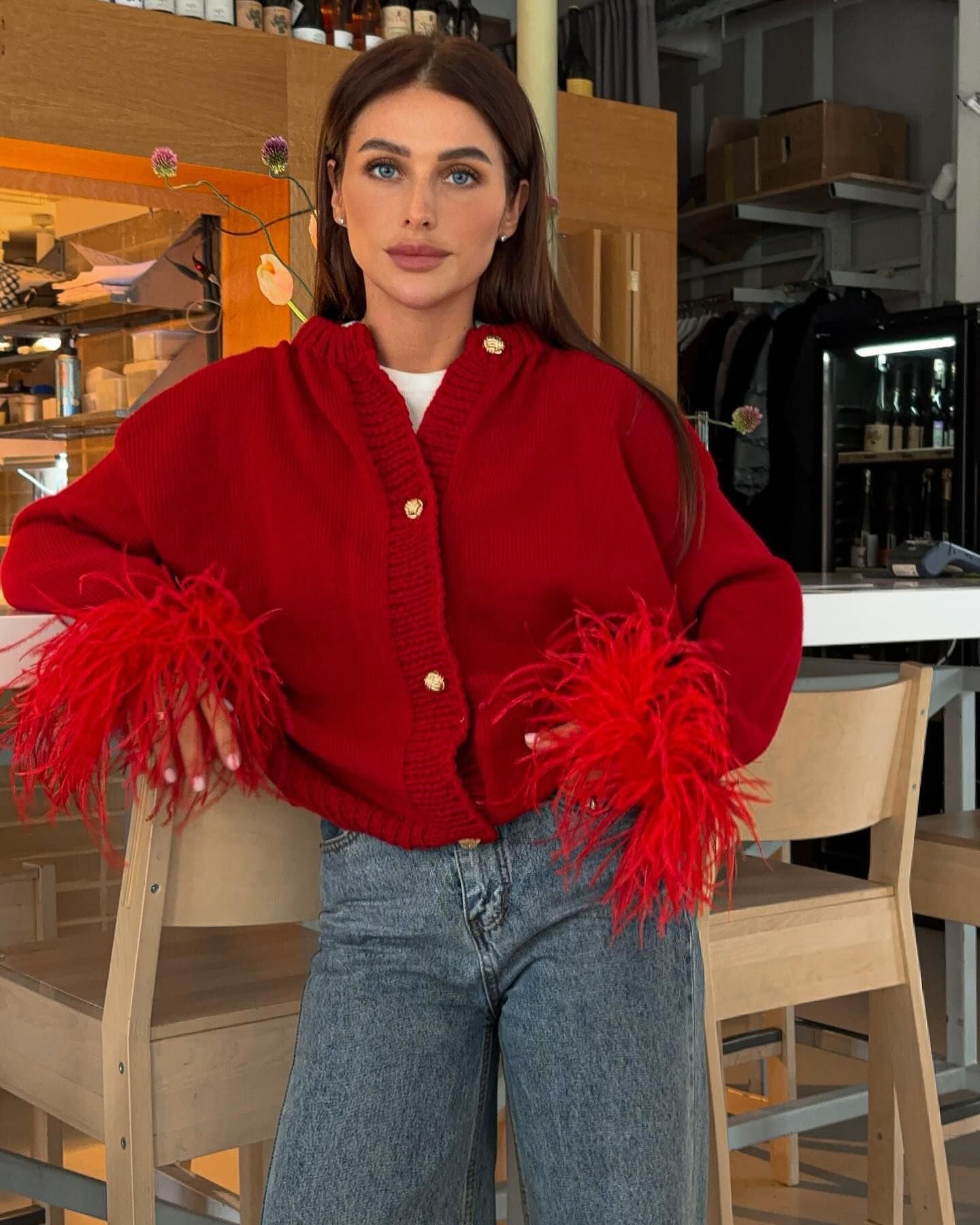 Elegante Strickjacke mit Federn an den Ärmeln und goldenen Knöpfen, erhältlich in Rot, Grau und Schwarz – perfekte Mischung aus Glamour und Komfort.