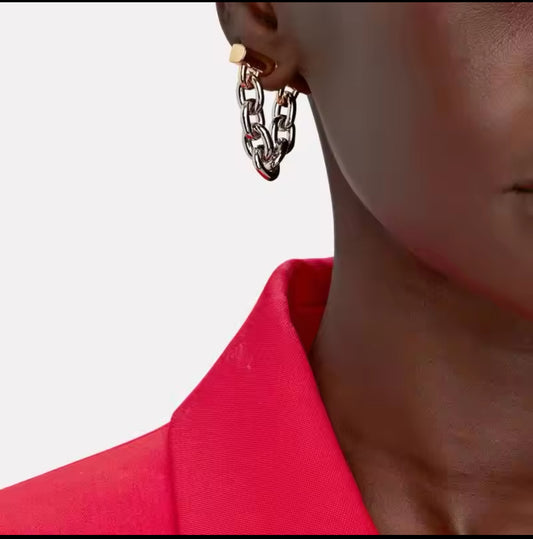Nahaufnahme eines stilvollen Ohrrings mit Kettendesign in Bicolor-Optik. Der Ohrring besteht aus einer Mischung aus gold- und silberfarbenen Gliedern, die an einer goldfarbenen Befestigung am Ohr befestigt sind. Der Schmuck verleiht einen modernen, edgy Look mit einem Hauch von Luxus.