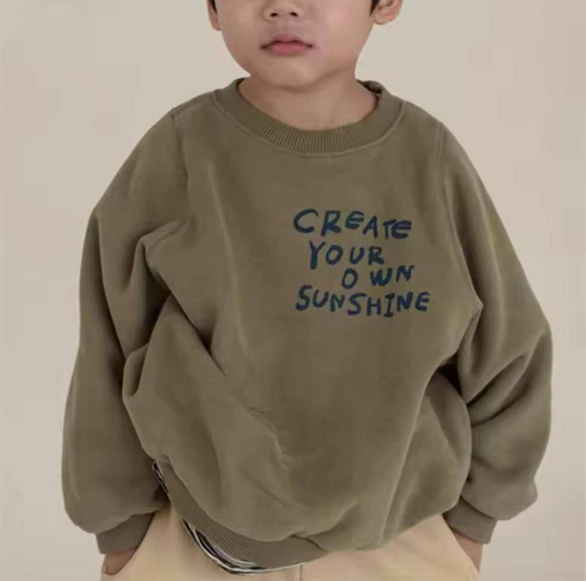 Junge mit olivgrünem Oversized Sweatshirt und motivierendem Print