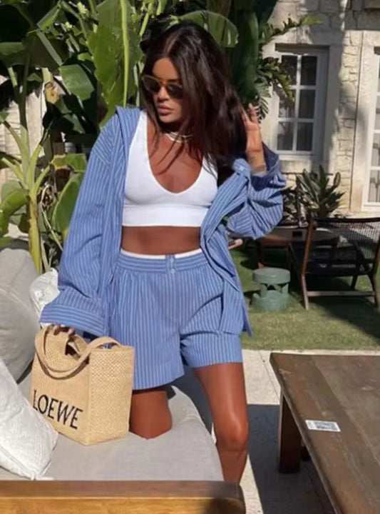 Frau trägt sommerlichen blauen Zweiteiler aus Hemd und Shorts im Streifenlook – kombiniert mit weißem Top und Basttasche
Produktbild: Blaues Zweiteiler-Set bestehend aus Oversized-Hemd und Shorts auf weißem Hintergrund